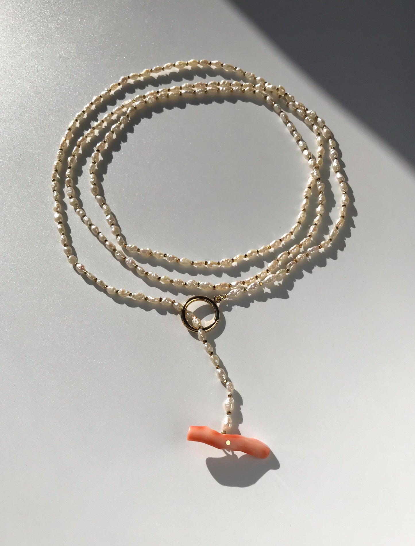 Freshwater pearl necklace with large pink coral bar