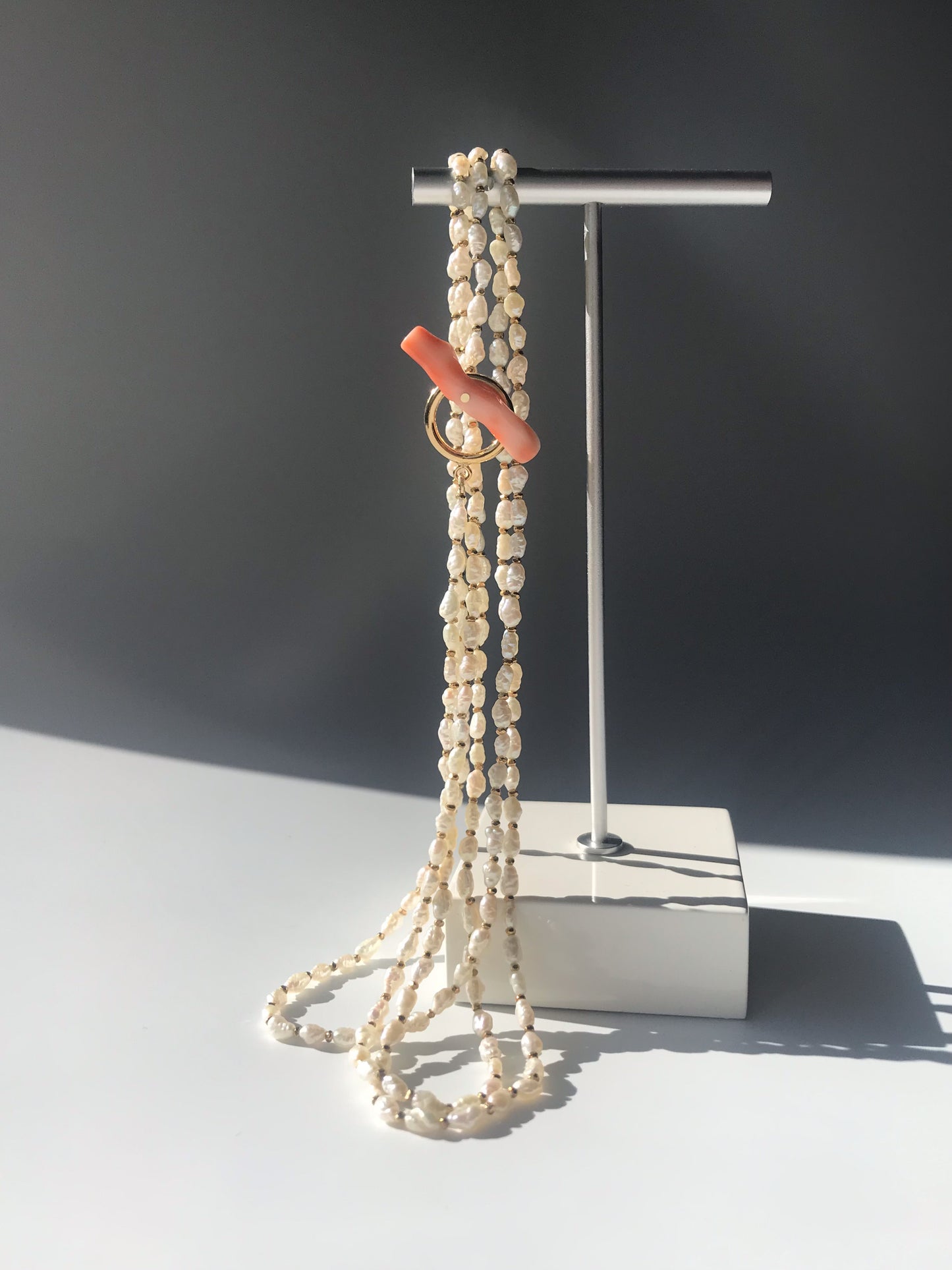 Freshwater pearl necklace with large pink coral bar